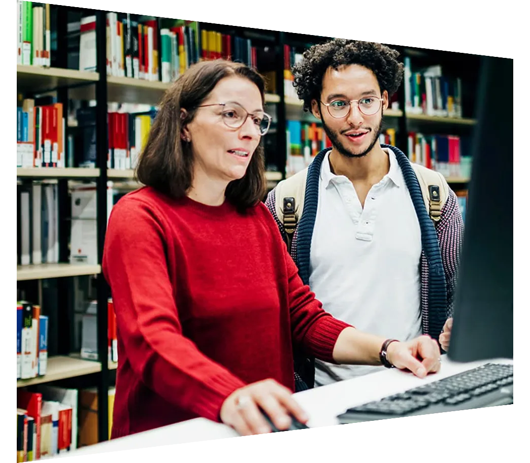 Librarian looking up books on computer for student