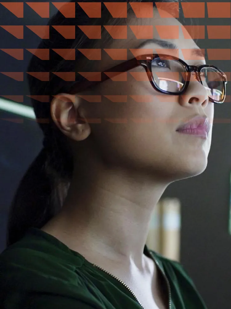 Young asian woman working at a desk with multiple monitors
