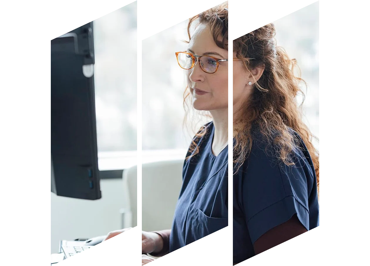 Female clinician with curly hair and glasses works at computer