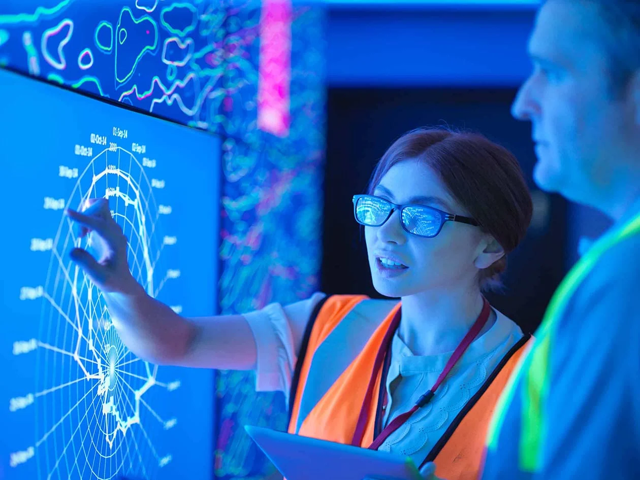 Two engineers examining geological data on a digital screen