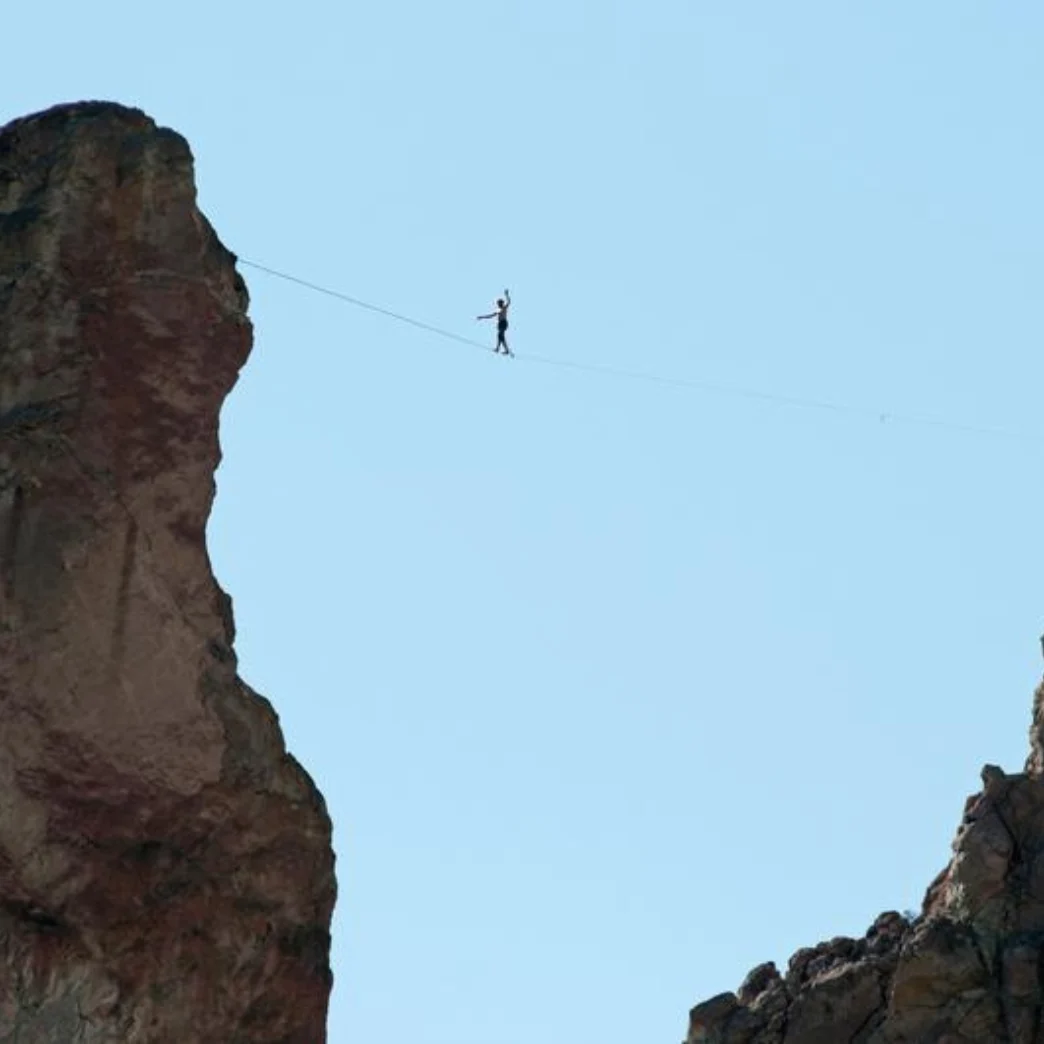 a person balancing on the line while reaching the other end of the mountain