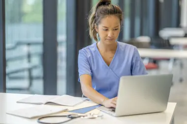 nurse working on laptop sitting at a table