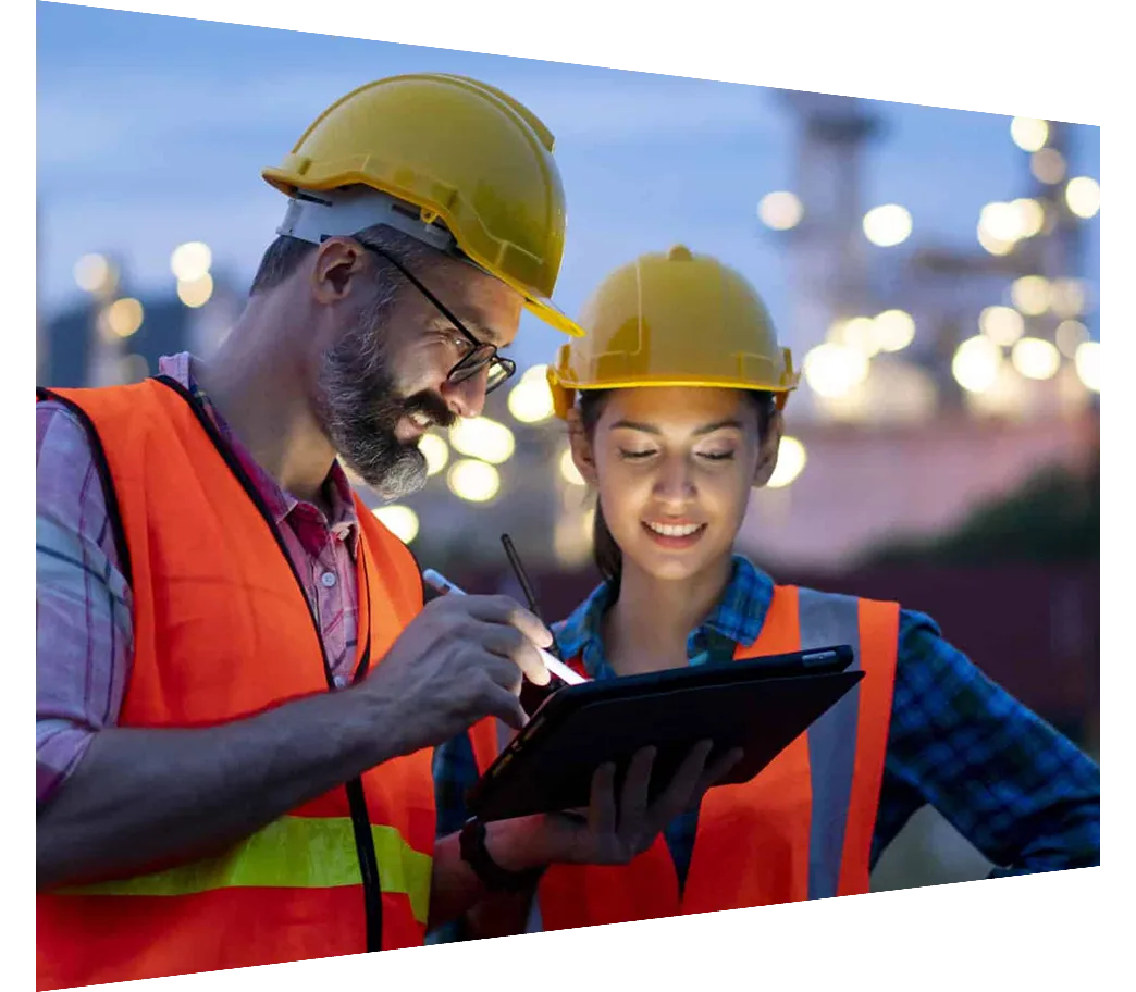 Engineers in front of an oil refinery reading a tablet
