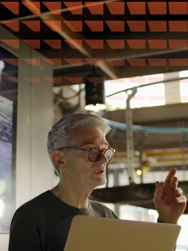 Mature man conducting a lecture with the aid of a large screen