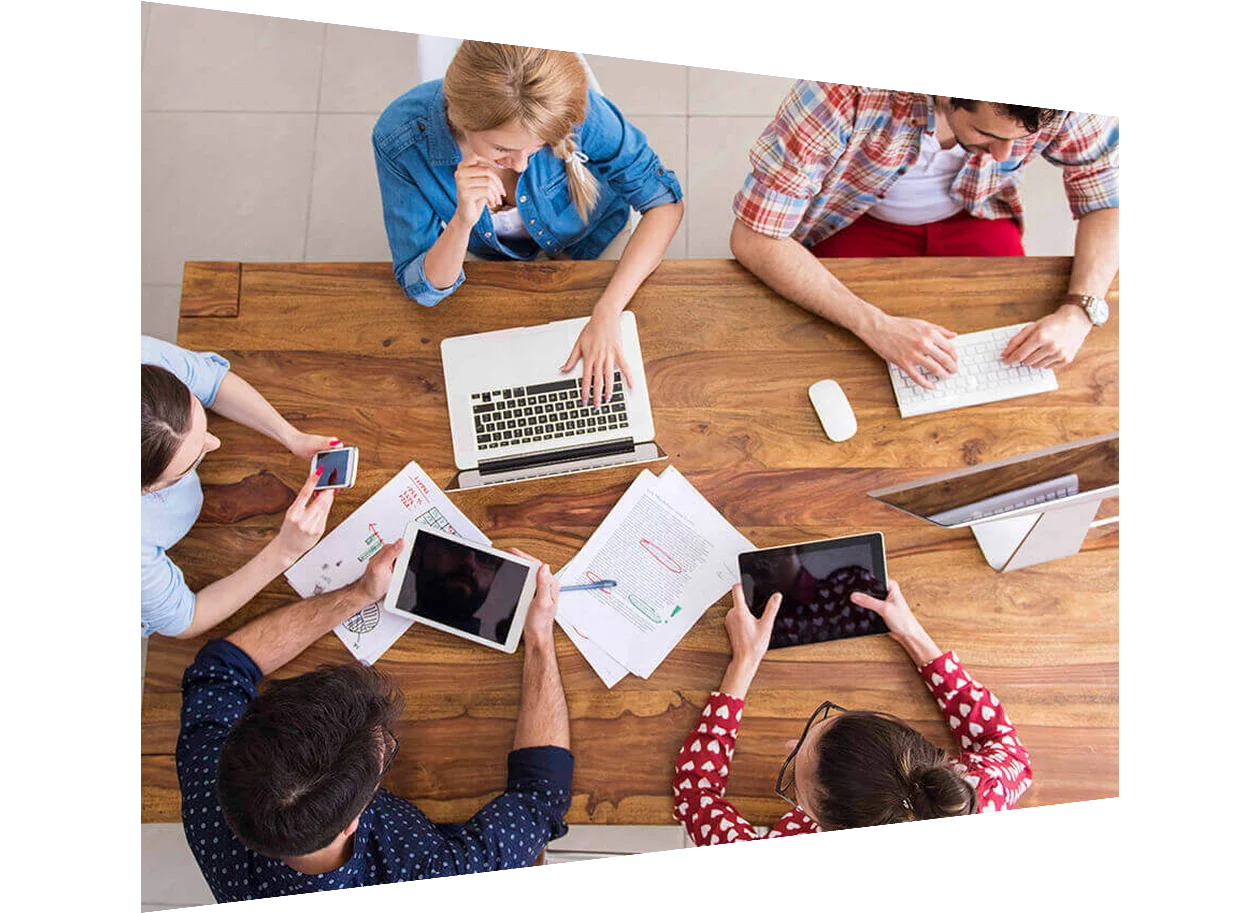 Above view of young students sitting round a table using digital devices