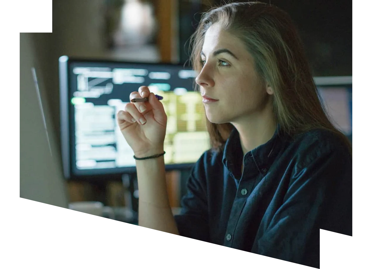 Young woman at desk surrounded by monitors displaying data