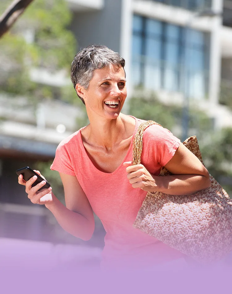 Femme d'âge moyen souriante avec un smartphone à la main