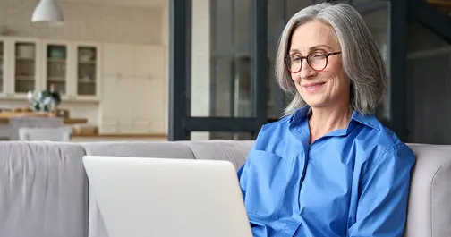 Femme d'âge moyen souriante avec un ordinateur portable