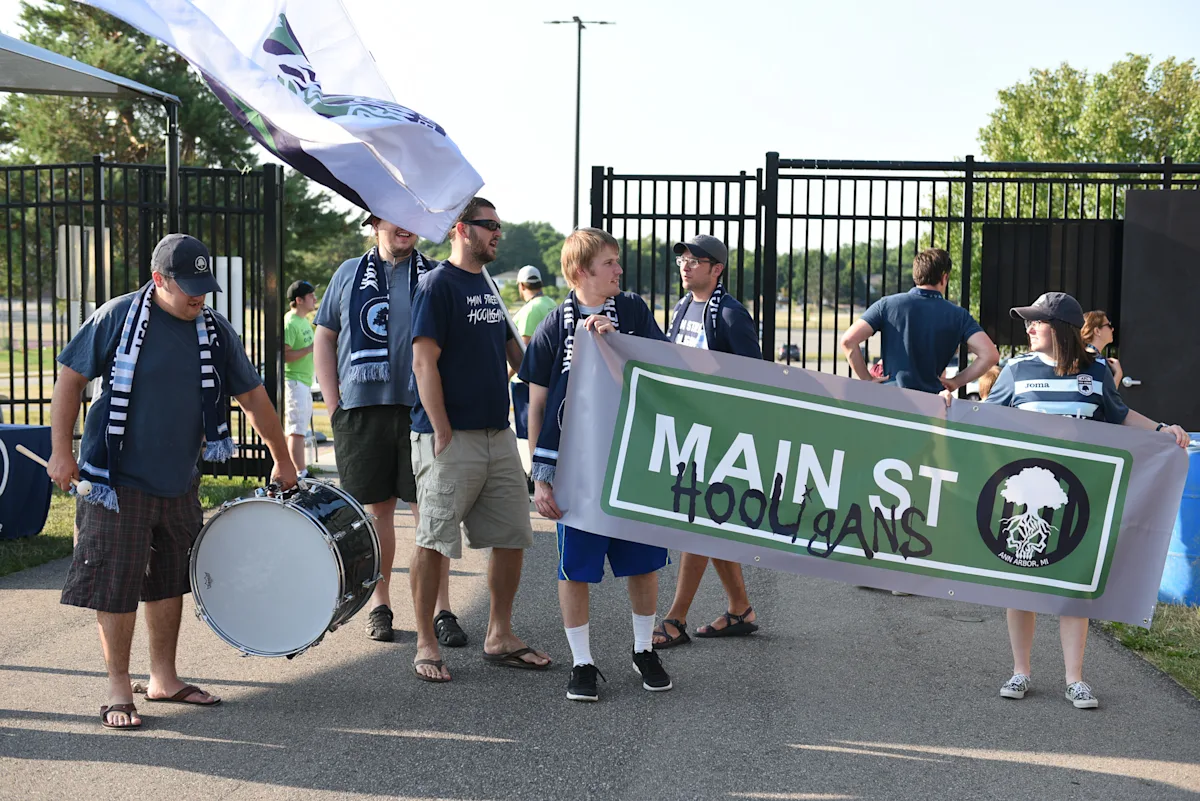 Main Street Hooligans march into the stadium with a drum, flags, and the MSH banner