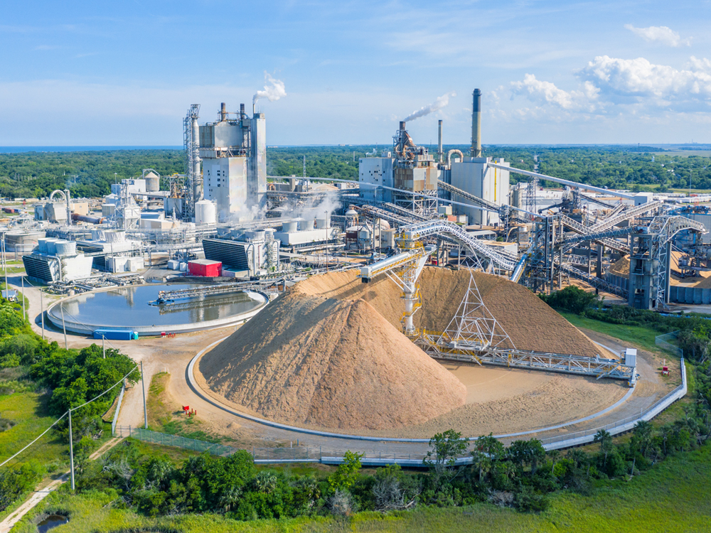 A large industrial scene with a pile of sand in the foreground. 