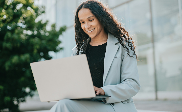 Person using a laptop outdoors in a city setting