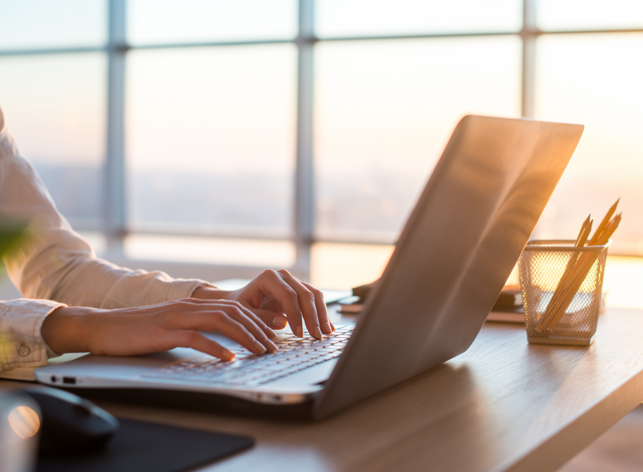 Person seated at a desk using a computer in a bright workspace