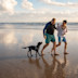Family walking with dog on beach