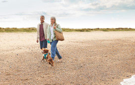 Couple walking their dog along the beach