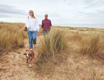 Couple walking their dog on the dunes at Seashore