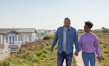 A couple stroll hand-in-hand through our Church Farm holiday park in Sussex.
