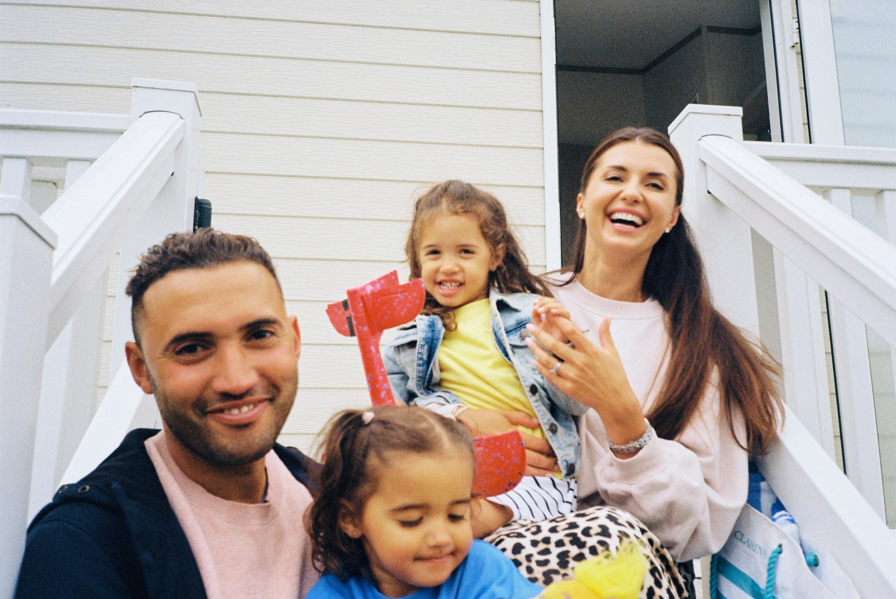 Family sitting on the steps outside their caravan.