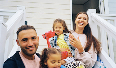 Family sitting on the steps outside their caravan.