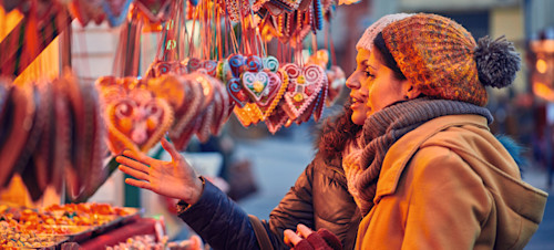 Friends peruse the sweet treats on a Christmas market stall.