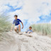 Two kids preparing to slide down a sand dune