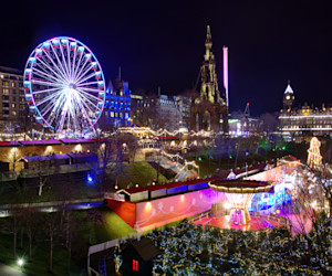 The famous Christmas Market at Edinburgh, Scotland. Night lights lit up setting a lovely scene against the night sky.