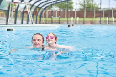 A family enjoy swimming in the new covered outdoor pool at Haven Hopton, Norfolk