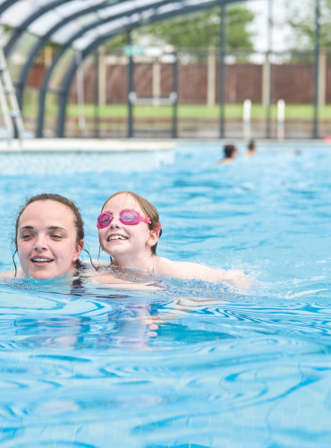 A family enjoy swimming in the new covered outdoor pool at Haven Hopton, Norfolk