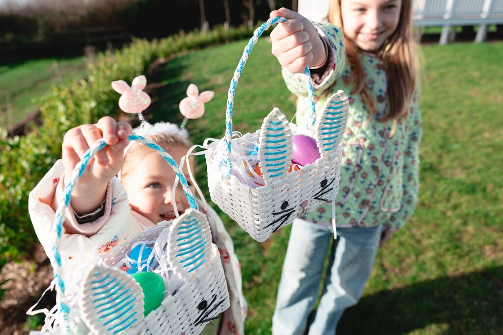 two sisters doing an easter egg hunt in the grass