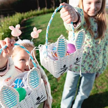 two sisters doing an easter egg hunt in the grass