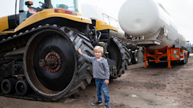 A little boy standing near a bulldozer (digger)