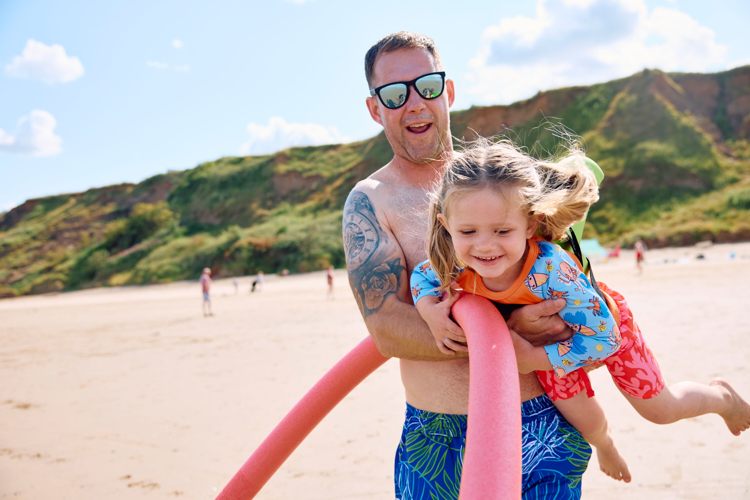 A Dad and daughter play together on the beach.