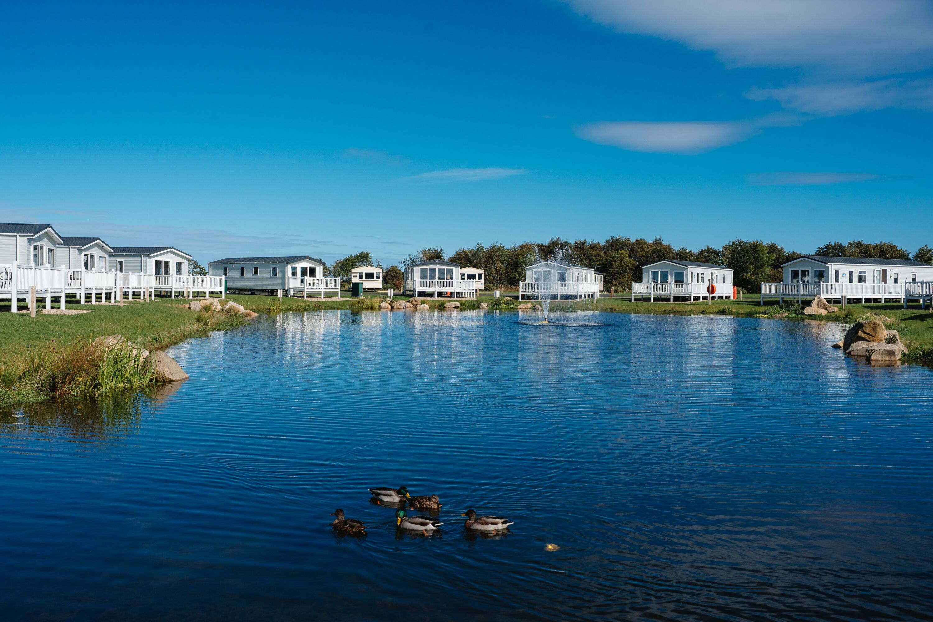 Caravans look out over a lake at Haggerston Castle Holiday Park.