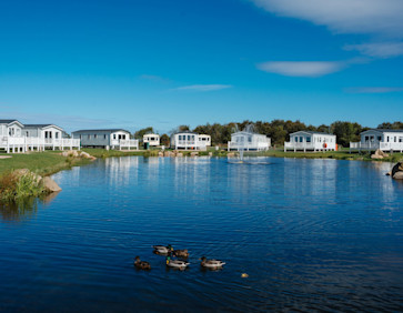Caravans look out over a lake at Haggerston Castle Holiday Park.