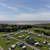 A drone image shows the Lakeland Leisure Park touring area with coastal views beyond it.