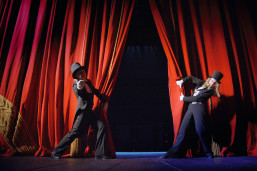 Performers opening the red curtains.