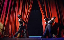 Performers opening the red curtains.