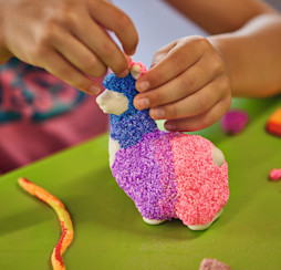 A child decorates a Llama-shaped piece of pottery.