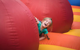 A young girl laughs among the obstacles on the inflatable arena.