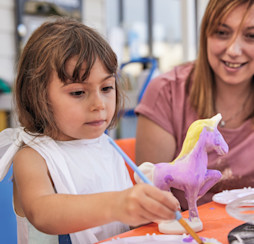 A young girl paints a unicorn.