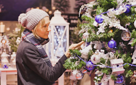 A woman admires a Christmas tree at a Christmas market.