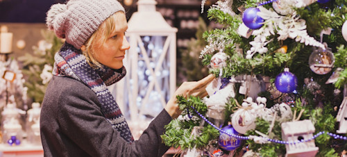 A woman admires a Christmas tree at a Christmas market.