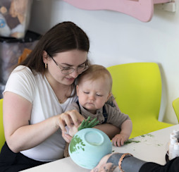 A tot adds his handprint design to a piece of pottery.