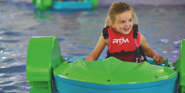 A young girl tries out the Aqua Paddlers activity in a pool at Haven