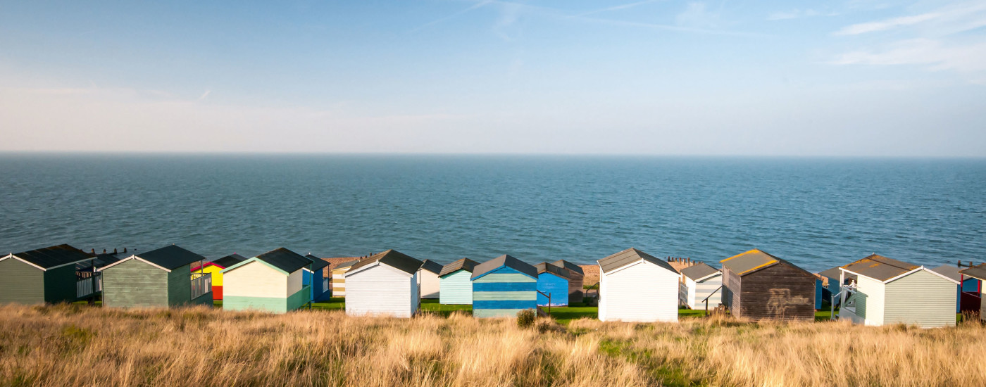 Colourful beach huts facing the calm Atlantic sea at Whitstable, Kent