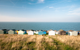Colourful beach huts facing the calm Atlantic sea at Whitstable, Kent