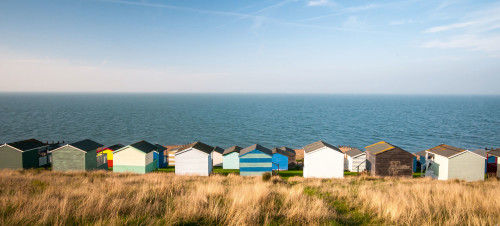 Colourful beach huts facing the calm Atlantic sea at Whitstable, Kent