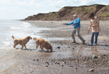 Couple walking the dog along the beach at Far Grange