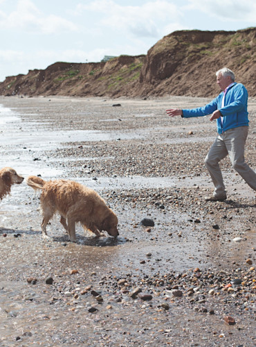 Couple walking the dog along the beach at Far Grange