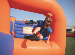 A guest jumping over the inflatables playing Nerf Training Camp