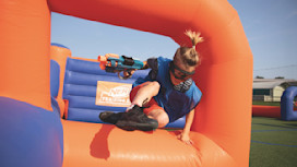 A guest jumping over the inflatables playing Nerf Training Camp